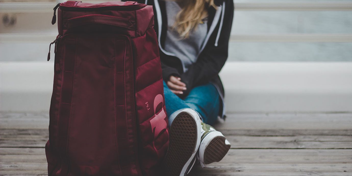 Girl sitting next to a large backpack