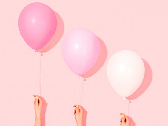 Women's Hands Holding Pink Balloons