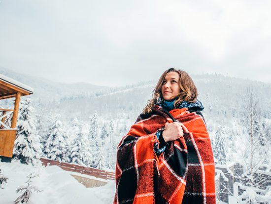 Woman Wearing Afghan Outisde Snowy Cabin