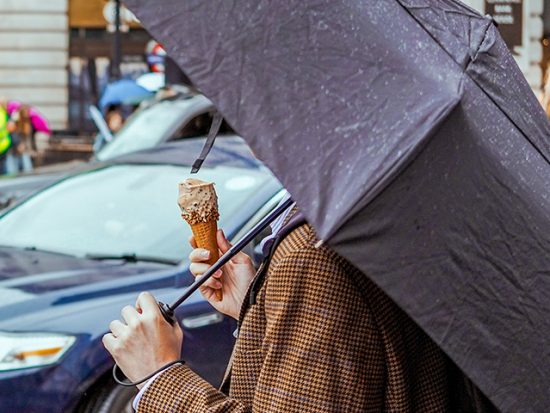 Woman Eating Ice Cream and Holding an Umbrella