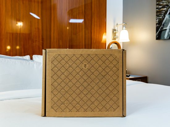 Trunk Club box filled with clothes from Nordstrom on a bed