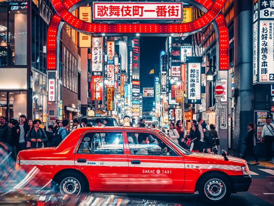 City streets of Tokyo at night, taxi driving past.