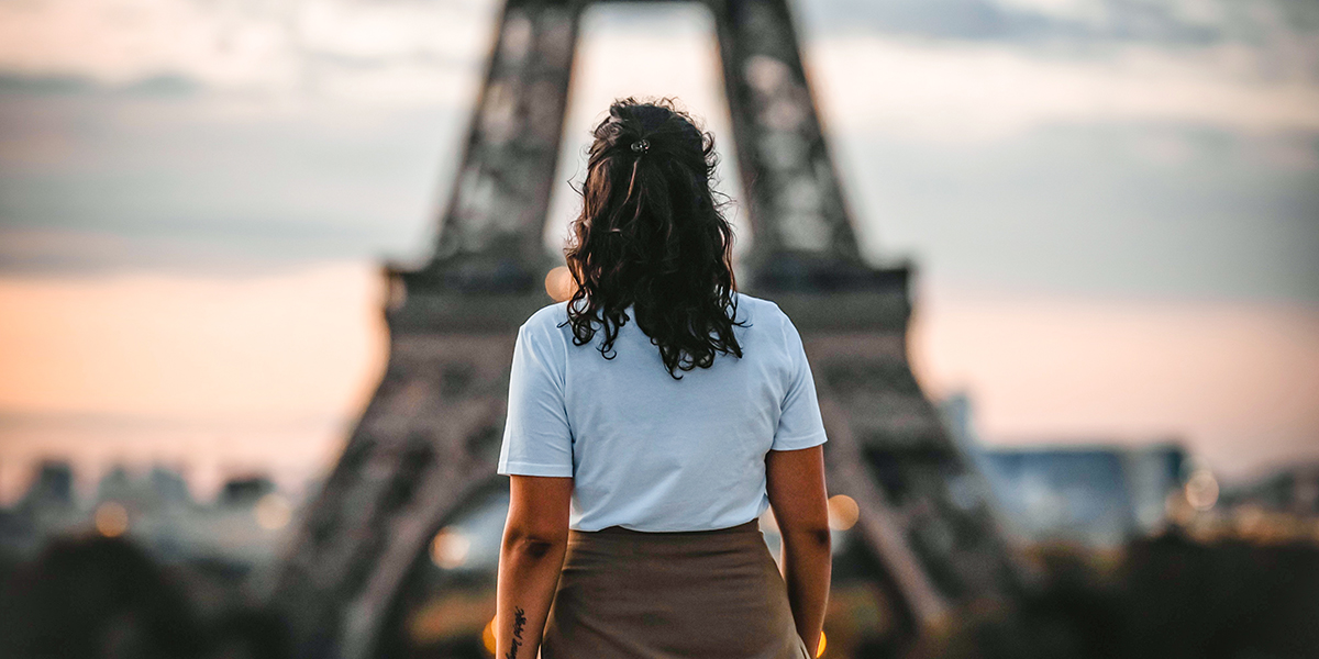 Woman standing in front of the Eiffel Tower at sunset