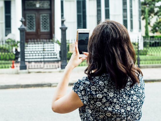 Woman taking a photo with her phone in the Garden District.