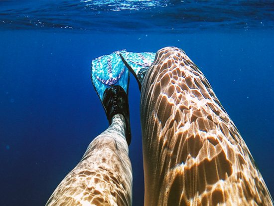 Woman's legs underwater with flippers on.