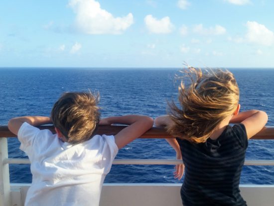 Kids looking out at the sea from a cruise ship.