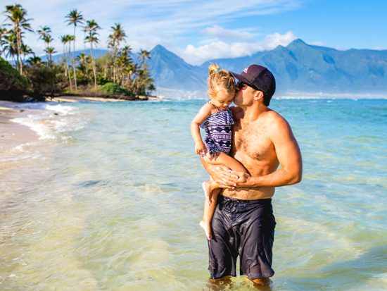 Man Holding His Daughter on a Beach.