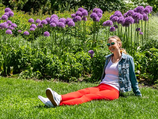 Megan sitting in the grass with flowers, wearing Fabletics.