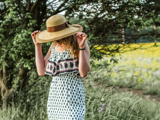 Woman wearing a Sun Hat standing in a field.