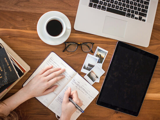 Woman writing in a journal at a desk.