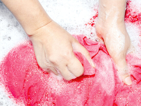 Hands washing laundry in a basin.