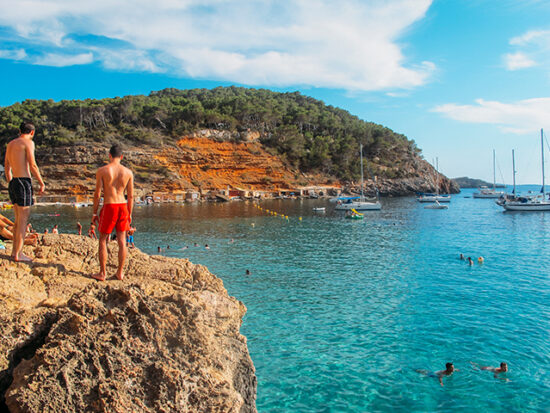 Two men waiting to cliff jump in Ibiza.