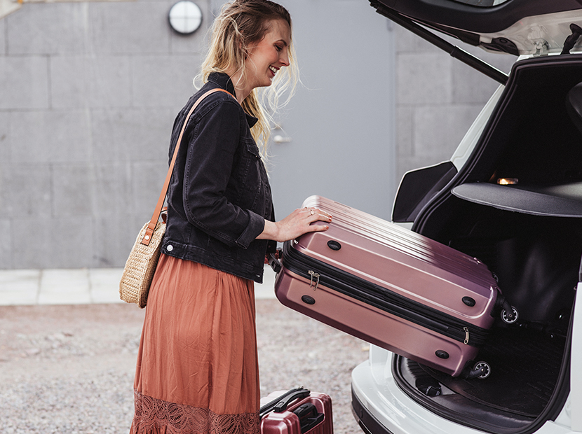 Woman putting two suitcases into the car.