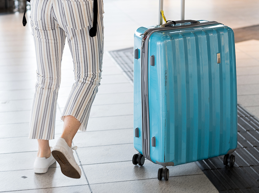 Woman rolling her suitcase into the airport.