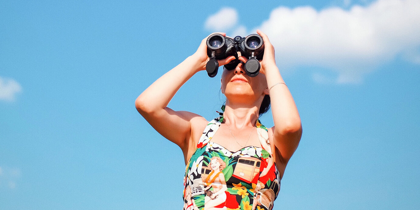 Woman standing looking through binoculars.